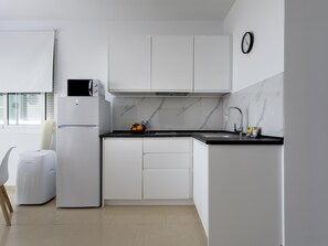 A modern kitchen with white cabinets, a built-in oven, a microwave, and a sink with a faucet. - Sunstay Flat Caribe. (Benalmádena)