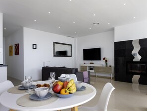Ein modernes Wohnzimmer mit Essbereich, einem Flachbildfernseher und einem Kamin.