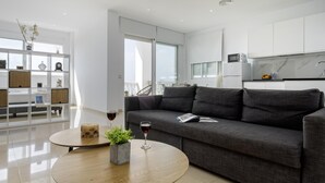 Ein modernes Wohnzimmer mit einem grauen Sofa, einem runden Couchtisch aus Holz und einem Glas Rotwein.