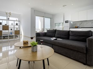 A modern living room with a grey sofa, a round wooden coffee table, and a glass of red wine. - Sunstay Flat Caribe. (Benalmádena)