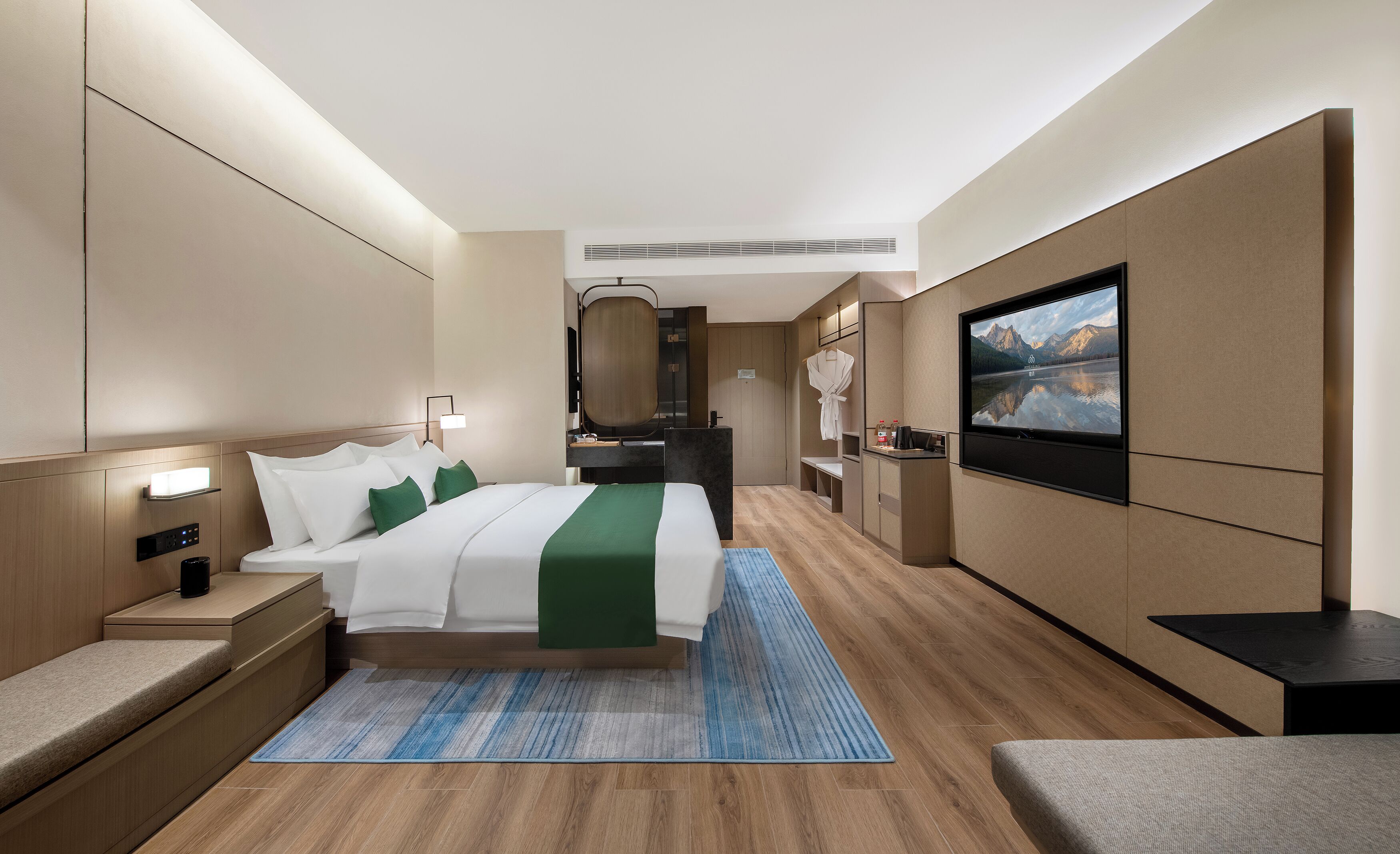A modern hotel room with a bed, bedside table, TV, and a bathroom.