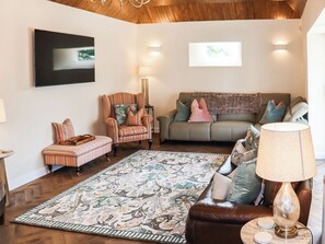 A living room with a patterned rug, a brown leather sofa, a striped armchair, and a green couch with multiple cushions.