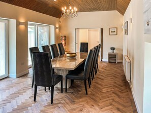 A dining area with a wooden table and chairs, a chandelier, and a herringbone floor pattern. - 5 bedroom accommodation in Auchtermuchty (Auchtermuchty)
