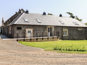 A stone building with a sloped roof, a front door, and a small porch with a railing. - 5 bedroom accommodation in Auchtermuchty (Auchtermuchty)