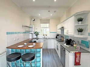 A modern kitchen with a bar area, white cabinetry, and a window providing natural light.