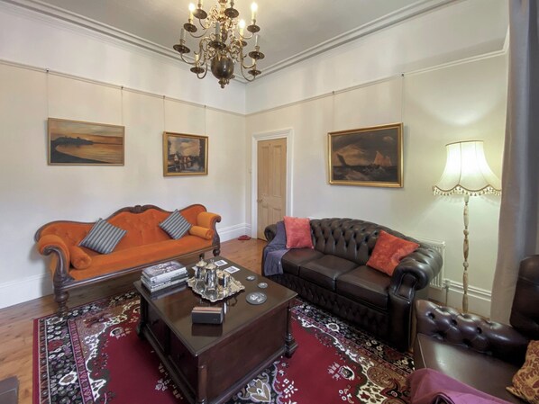 A room with two sofas, a coffee table, and a chandelier.