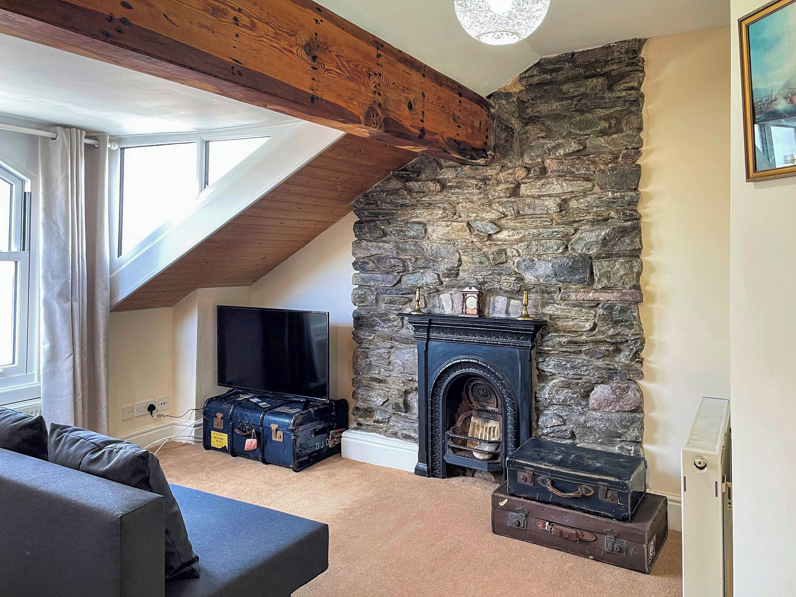 A room with a stone fireplace, a television, and luggage.