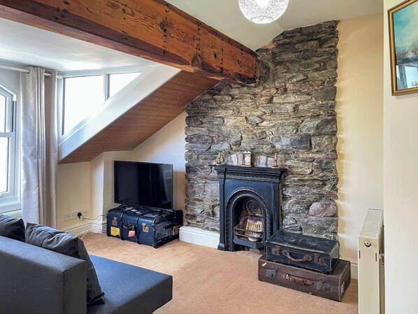 A room with a stone fireplace, a television, and luggage.