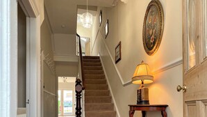 A staircase leading to an upper floor, a wall-mounted lamp, and a door with a glass panel.