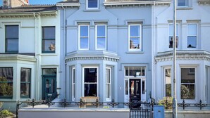 A row of townhouses with bay windows, a front door, and a small bench.