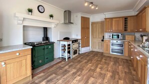 A kitchen with wooden cabinets, a green stove, a white countertop, and a microwave.