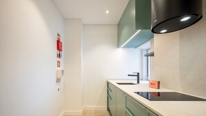 A modern kitchen with a black range hood, a sink, and green cabinets. - GuestReady – Romantic Lisbon Nook (Lisbon)