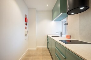 A modern kitchen with a black range hood, a sink, and green cabinets. - GuestReady – Romantic Lisbon Nook (Lisbon)