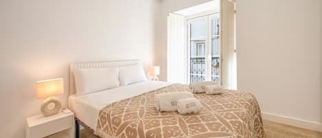 Une chambre d’hôtel avec un lit, des lampes de chevet, une table de chevet et une vue sur le balcon extérieur.