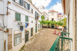 A narrow cobblestone street between buildings with balconies, some with laundry hanging. - GuestReady – Romantic Lisbon Nook (Lisbon)