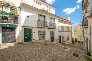 A cobblestone street with buildings featuring balconies and traditional windows. - GuestReady – Romantic Lisbon Nook (Lisbon)