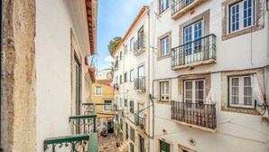 A narrow street with buildings on either side, featuring balconies with metal railings and a cobblestone path. - GuestReady – Romantic Lisbon Nook (Lisbon)