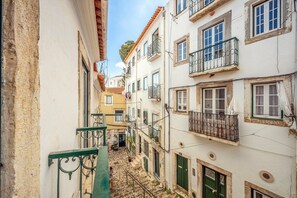 A narrow street with buildings on either side, featuring balconies with metal railings and a cobblestone path. - GuestReady – Romantic Lisbon Nook (Lisbon)