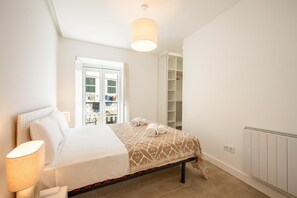 A bedroom with a bed, bedside lamp, and a wardrobe. - GuestReady – Romantic Lisbon Nook (Lisbon)