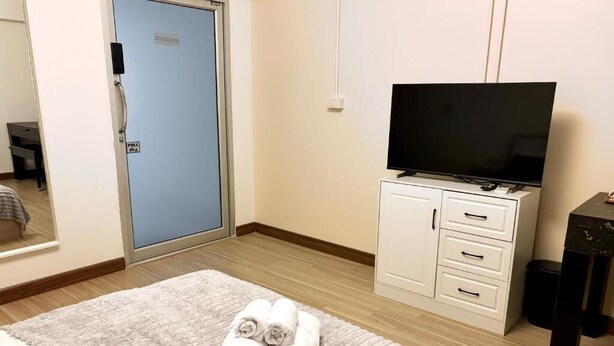 Ett hotellrum med en säng, en tv-apparat på ett skåp, en dörr och ett fönster.