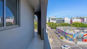 Un balcón con vista a una calle de la ciudad, edificios y un mural colorido.