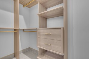 Ein Kleiderschrank mit offenen Regalen und Schubladen, mit heller Holzoptik und goldenen Griffen.