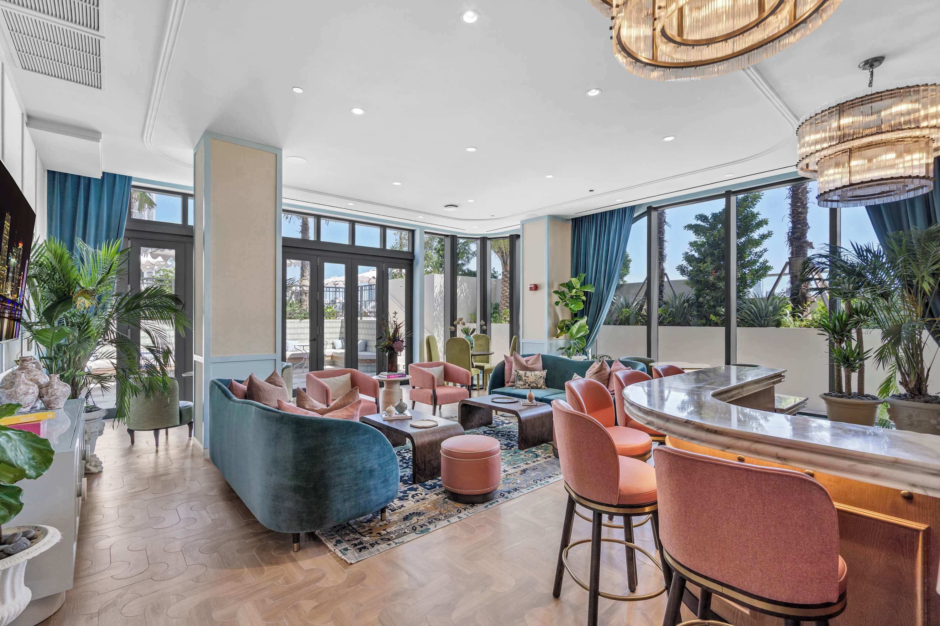 Un hall d’hôtel moderne avec un bar aux lignes courbes, des espaces de détente et de grandes fenêtres.