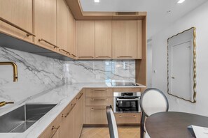 Une cuisine moderne dotée de plans de travail en marbre, d’armoires en bois et d’un four Bosch.