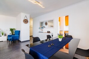Un coin repas moderne avec une table en verre, une nappe bleue et un fauteuil bleu.