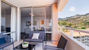 Ein Balkon mit Tisch und Stühlen, einer Couch und Blick auf eine Hügelterrasse.