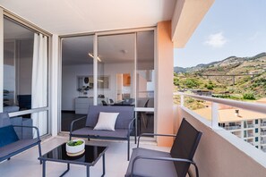 Ein Balkon mit Tisch und Stühlen, einer Couch und Blick auf eine Hügelterrasse.