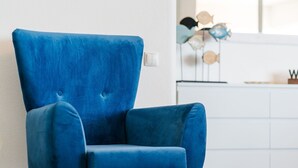 Ein blauer Sessel mit hoher Rückenlehne und gepolstertem Sitz, vor einer weißen Wand platziert.