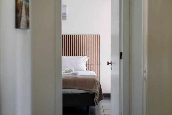 Une chambre d’hôtel avec un lit, une tête de lit en bois et une porte donnant sur une autre pièce.