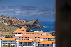 Eine Küstenstadt mit Häusern mit orangen Dächern, einem markanten Felsen und Blick auf das Meer.