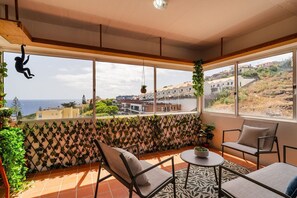 A balcony with a view of the sea, a seating area with chairs and a table, and a plant wall. - GuestReady - Oceanview Retreat in Caniço (Caniço de Baixo)
