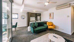 A modern living room with a green sofa, a yellow armchair, and a white coffee table. - Two Bedroom Sanctuary in the Valley (Fortitude Valley)