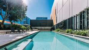 A swimming pool with lounge chairs and a modern building in the background. - Two Bedroom Sanctuary in the Valley (Fortitude Valley)