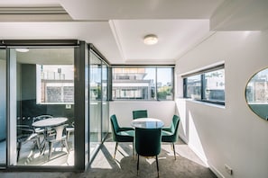 Ein modernes Zimmer mit einer Glaskabine, einem runden Tisch und grünen Stühlen.