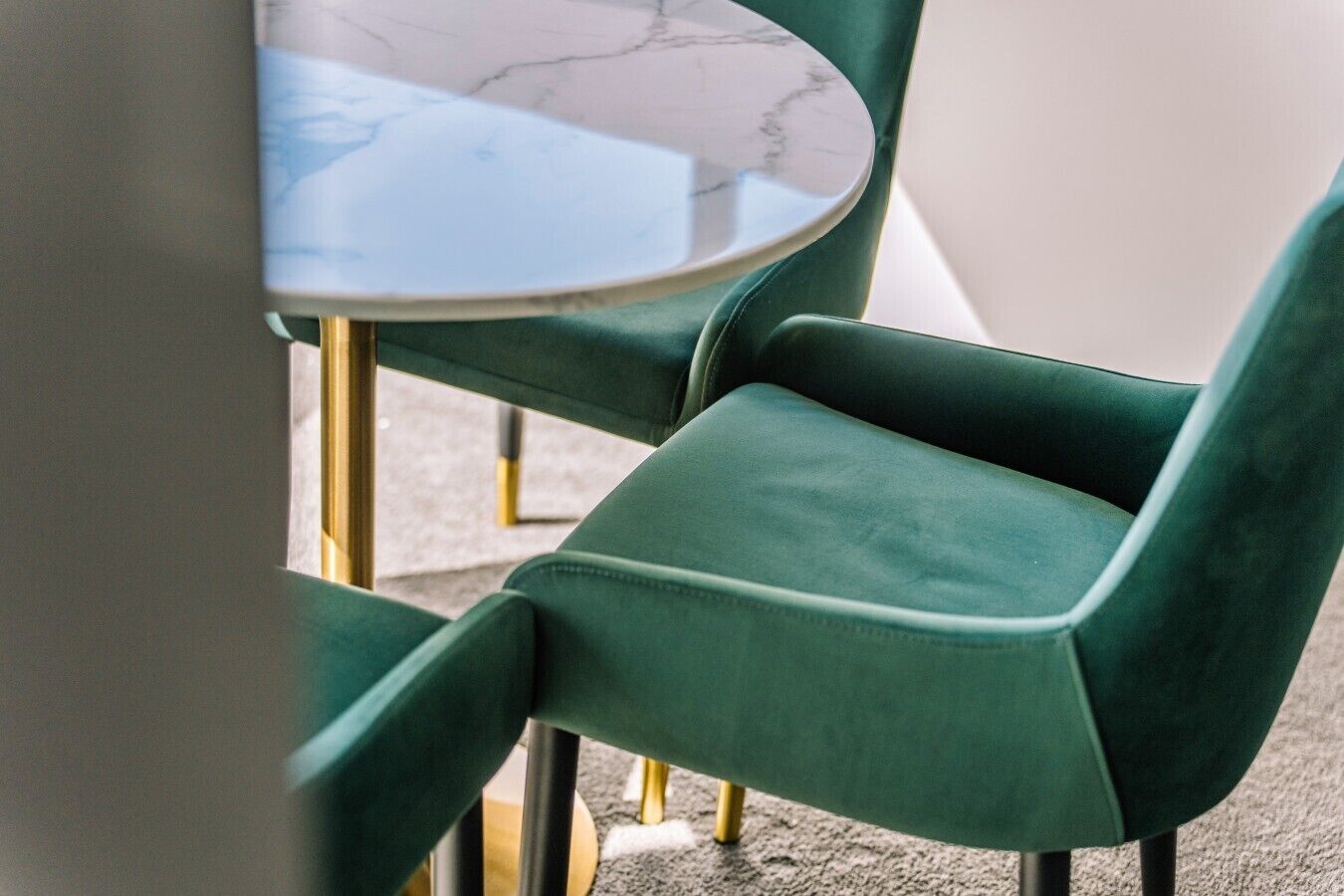 Uma cadeira estofada verde com mesa de tampo em mármore.