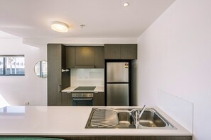 Eine moderne Küche mit einem Edelstahl-Kühlschrank, einem eingebauten Backofen und einer weißen Arbeitsplatte.