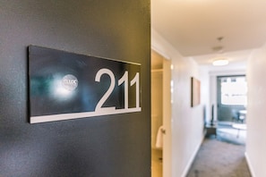 A hotel room number sign on a dark wall, indicating room 211. - Two Bedroom Sanctuary in the Valley (Fortitude Valley)