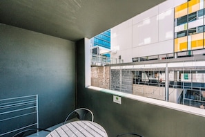 A balcony with a view of a modern building, a table, and a chair. - Two Bedroom Sanctuary in the Valley (Fortitude Valley)