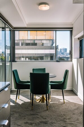 Ein moderner Büroarbeitsplatz mit einem runden Tisch, vier Stühlen, großen Fenstern und Blick auf die Stadt sowie einem Teppichboden.