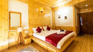 A wooden-paneled room with a bed, a bedside lamp, and a ceiling fan.