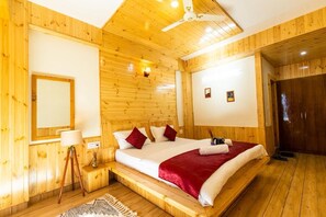 A wooden-paneled room with a bed, a bedside lamp, and a ceiling fan.
