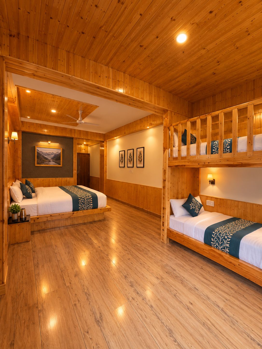 A wooden-floored room with two beds, a ceiling fan, and framed artwork on the walls.