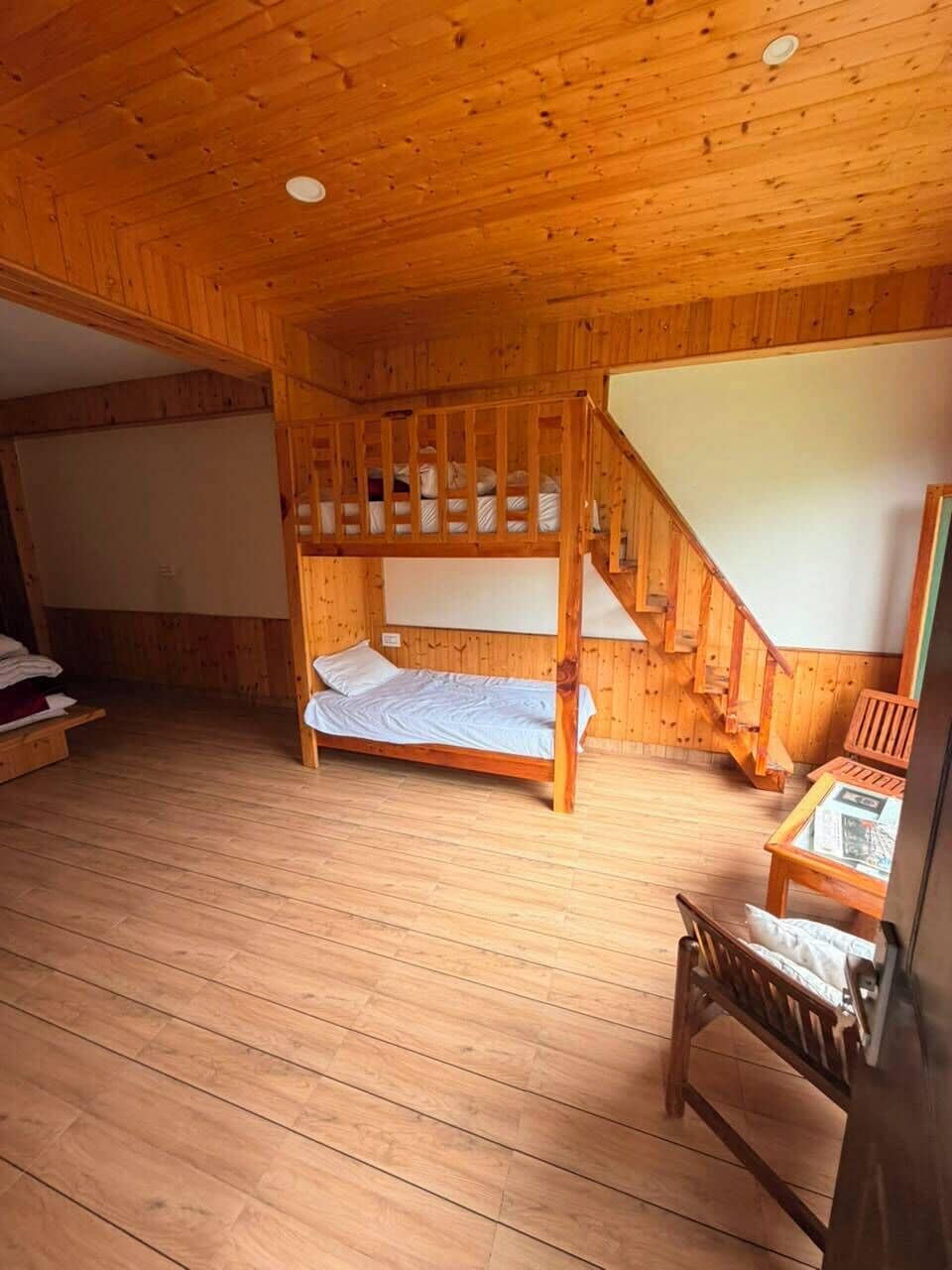 Una habitación con piso de madera, una litera, un escritorio y una silla.