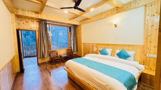 A wooden-paneled bedroom with a large bed, a ceiling fan, and a view of the outdoors through a window.