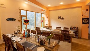 A dining area with a brick wall, a large window, and a bookshelf.
