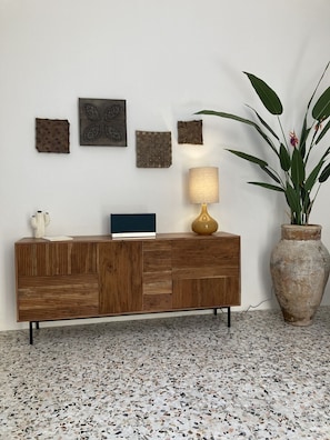 A wooden cabinet with a laptop, a lamp, and a potted plant against a white wall. - Casa Fioraliso, a cozy retreat in the heart of Noto's historic center. (Noto)